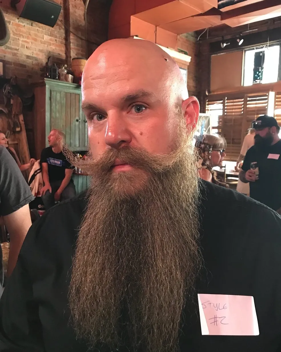 A bald man with long beard and mustache.