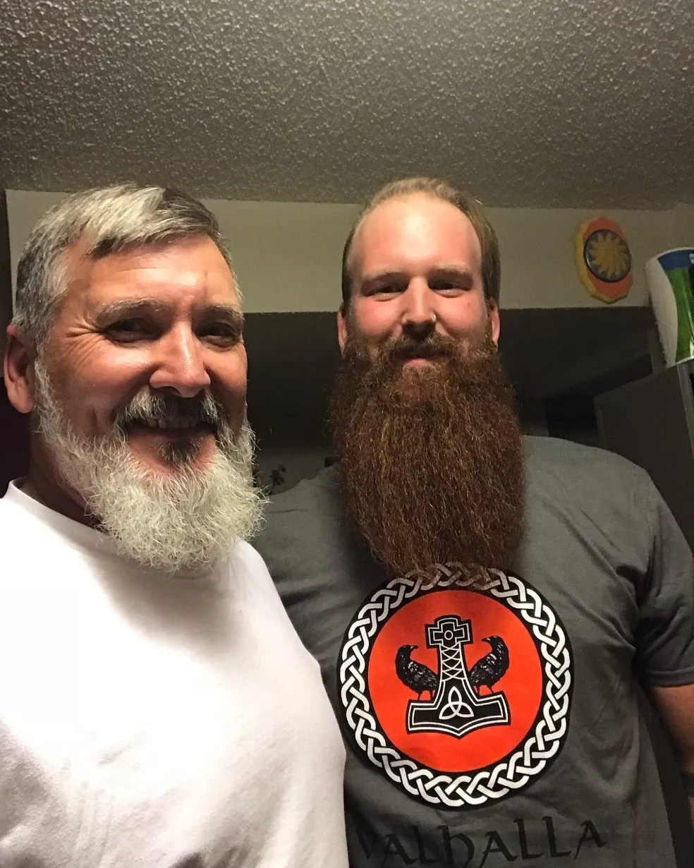 Two men with long beards and a beard logo on their shirt.