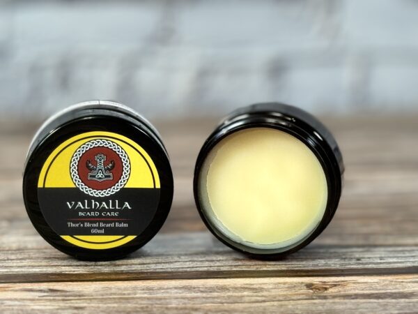 A couple of jars of balm sitting on top of a table.