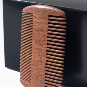 A wooden comb is sitting on top of a box.
