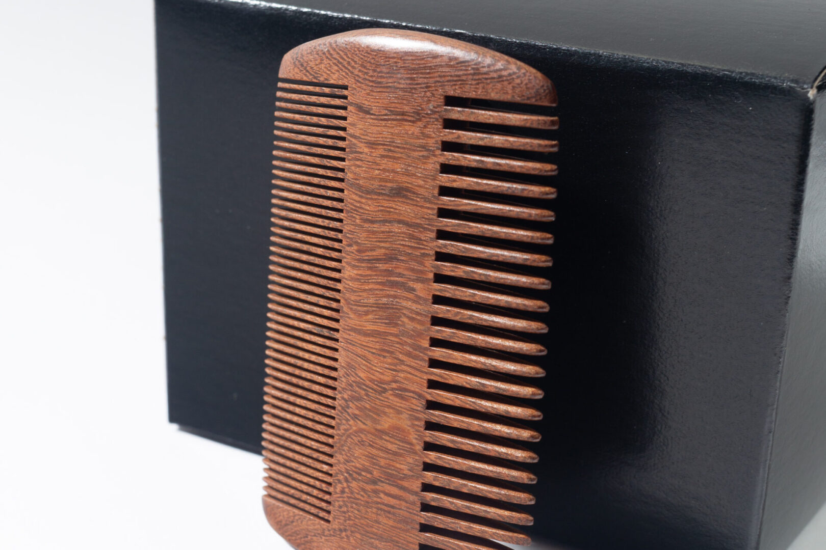 A wooden comb is sitting on top of a box.