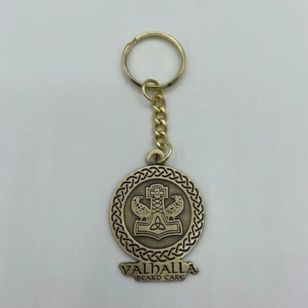 A gold key chain with a seal of valhalla on it.