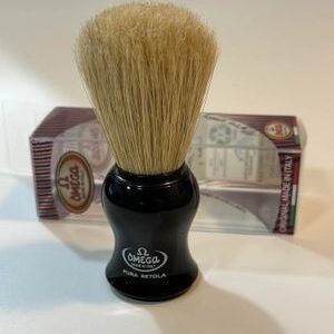 A black shaving brush sitting on top of a counter.