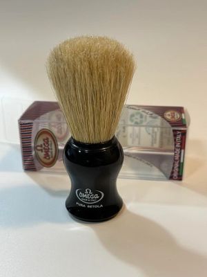 A black shaving brush sitting on top of a counter.